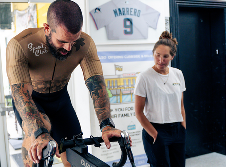 Scott Britton (ceo battle cancer) getting a guru bike fit from rachel at mack cycle. he is pictured wearing an assos gold speedclub jersey.