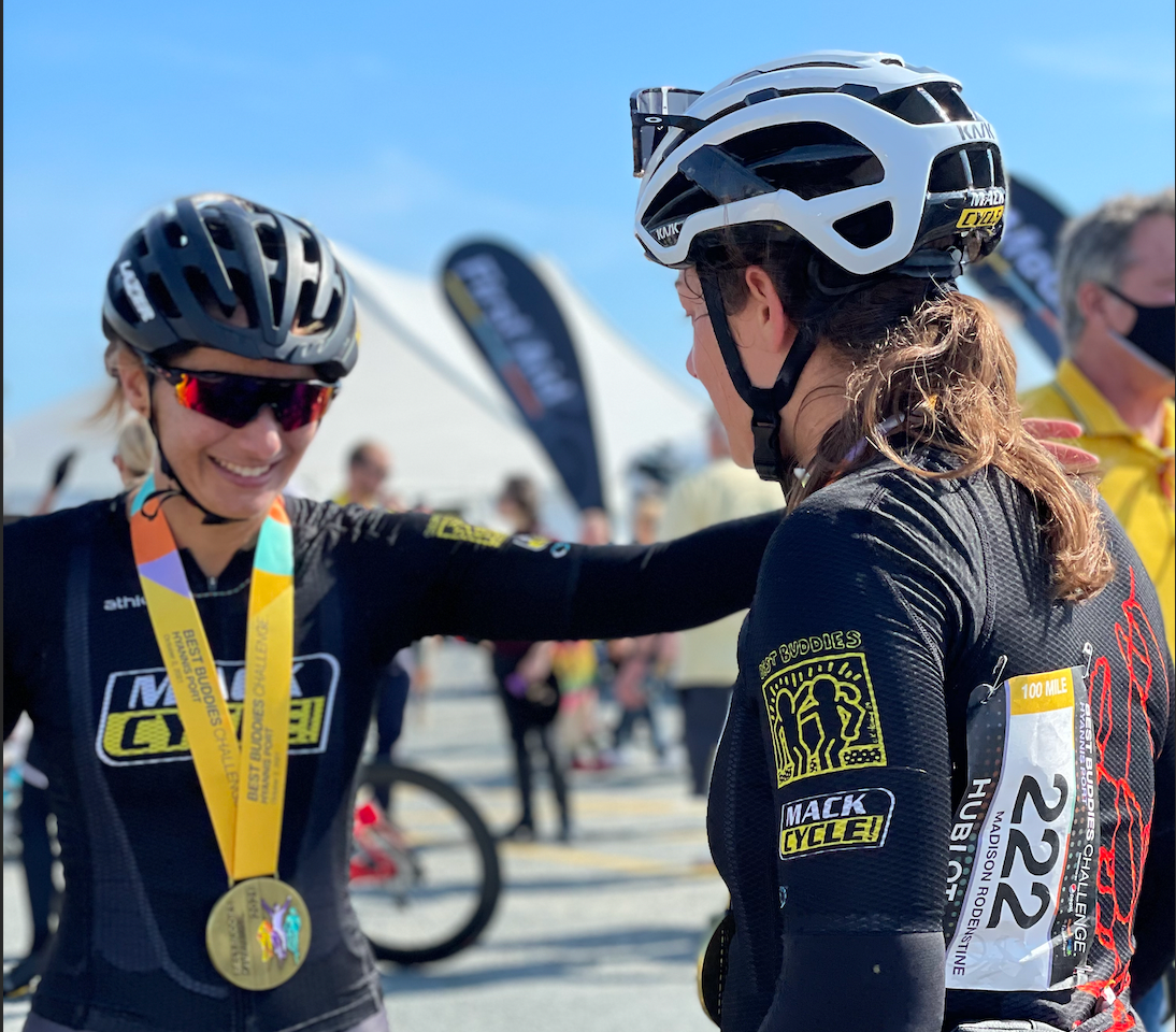 Rachel and Madi Rodenstein of Team Mack Cycle, adorned with their medals,  prepare to embrace at the finish line of the Best Buddies Challenge Hyannis Port at Craigsville Beach in Cape Cod. The Sky is Blue and the sun is shinning.