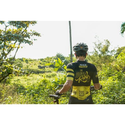 Bavie Grafals looking out over the greenery at the Virginia Key Mountain Bike Trails in Miami. She is wearing her Mack Cycle black and yellow "original ride" cycling kit