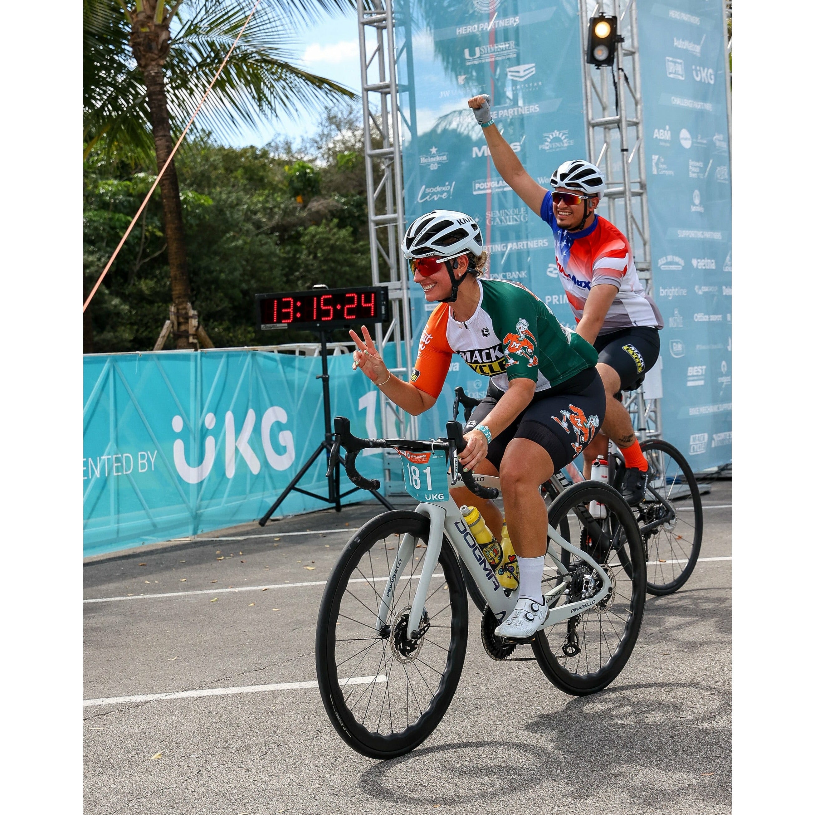 ZENAIDA CROSSING THE FINISH LINE OF THE DOLPHINS CHALLENGE CANCER 2022 ON HER PINARELLO DOGMA F WITH PRINCETON WHEELS. SHE IS WEARING THE TEAM HURRICANES MACK CYCLE SEBASTIAN THE IBIS CYCLING KIT.