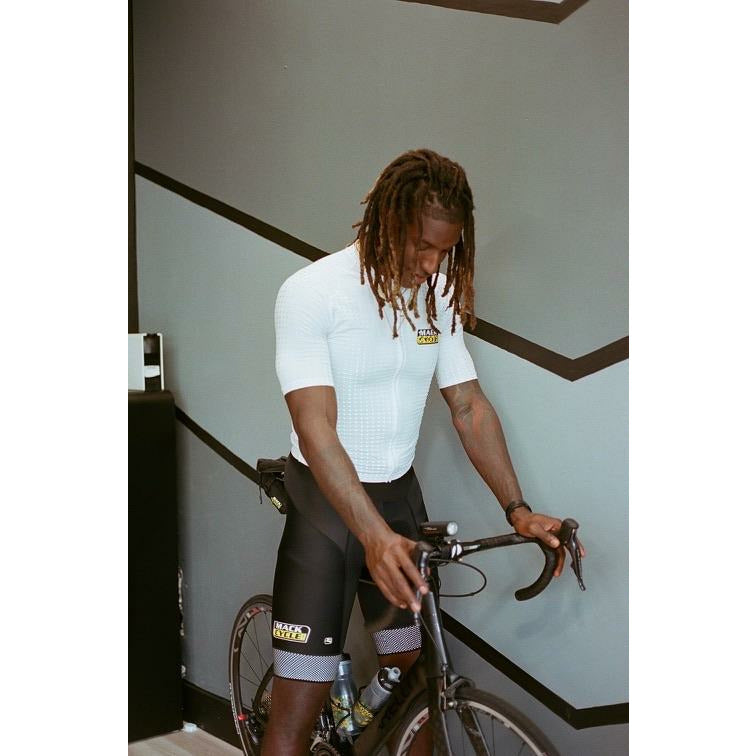 Reese Whitely wears his white reflective cycling kit from mack cycle while posing with his Pinarello Prince inside Complex Health and Wellness in South Miami